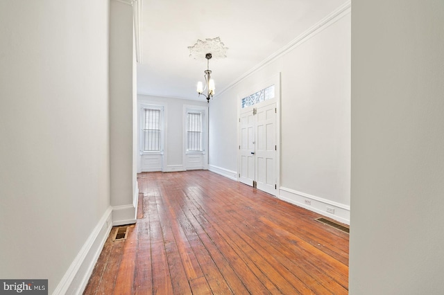 entryway with ornamental molding, a chandelier, and hardwood / wood-style flooring