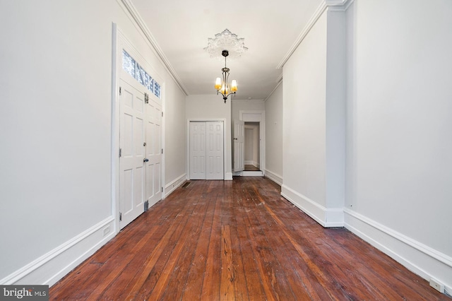 entryway with crown molding, a chandelier, and dark wood-type flooring