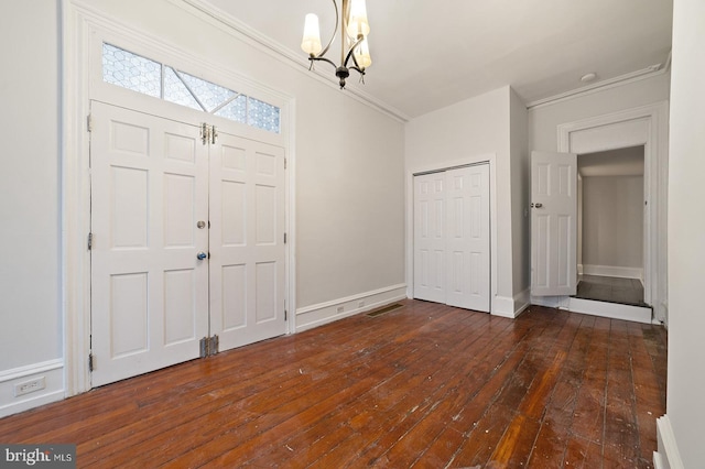 entrance foyer with ornamental molding, a chandelier, and dark hardwood / wood-style floors