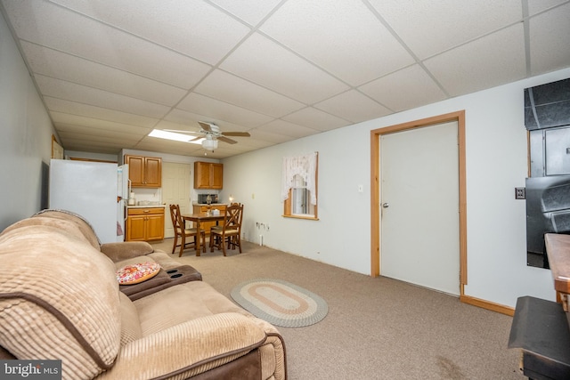 living room with a drop ceiling, light colored carpet, and ceiling fan