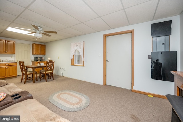 living room with a drop ceiling, light colored carpet, and ceiling fan