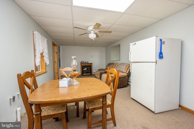 dining room featuring a paneled ceiling, light carpet, and ceiling fan