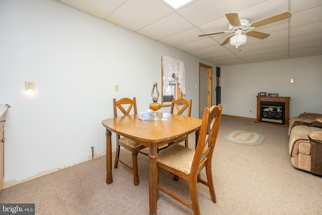 carpeted dining area featuring a paneled ceiling and ceiling fan