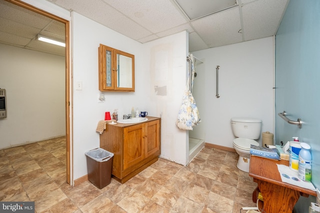 bathroom with vanity, a paneled ceiling, toilet, and walk in shower