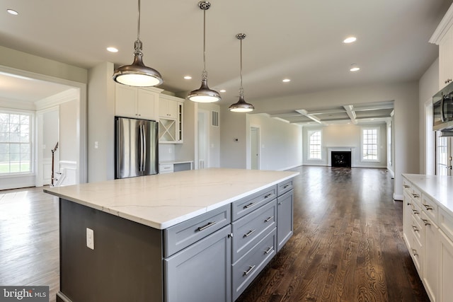 kitchen featuring beamed ceiling, hanging light fixtures, white cabinets, stainless steel refrigerator, and dark hardwood / wood-style flooring