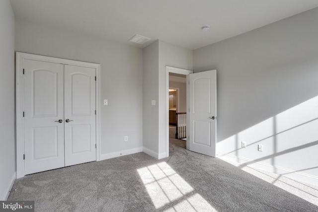 unfurnished bedroom with a closet and light colored carpet