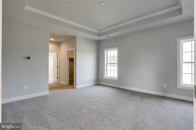 empty room featuring light carpet, ornamental molding, and a tray ceiling