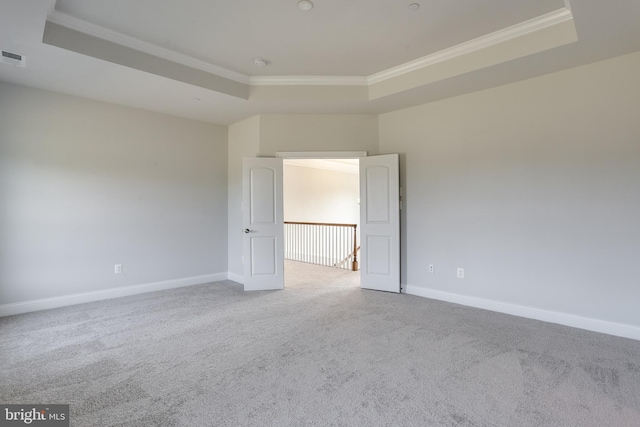 carpeted spare room featuring crown molding and a tray ceiling