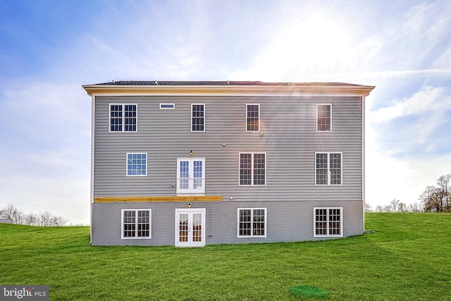 back of house with french doors and a lawn