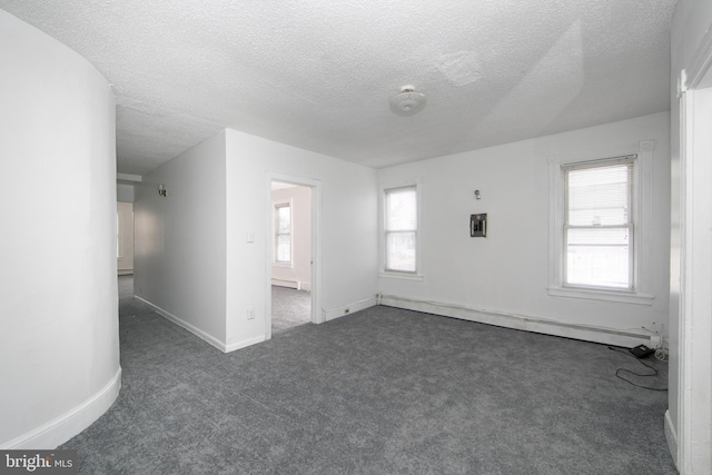 unfurnished room featuring dark colored carpet, a textured ceiling, and a wealth of natural light