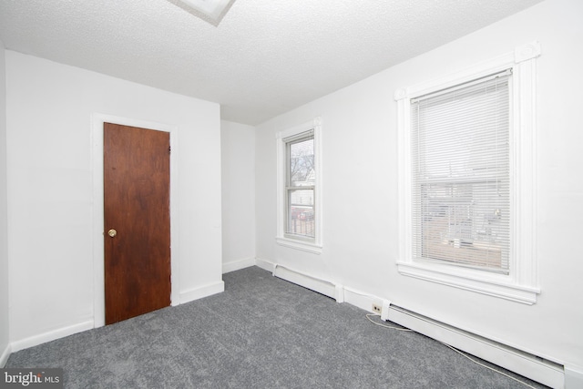 spare room featuring a textured ceiling, dark carpet, and baseboard heating