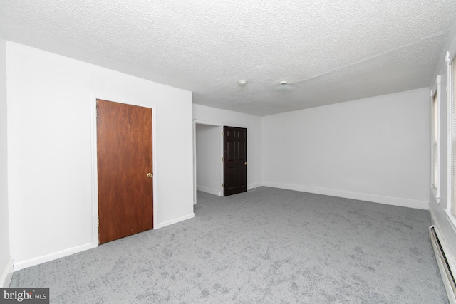 carpeted spare room with a textured ceiling and a baseboard radiator