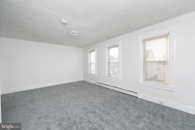 spare room with dark colored carpet, a wealth of natural light, a textured ceiling, and baseboard heating