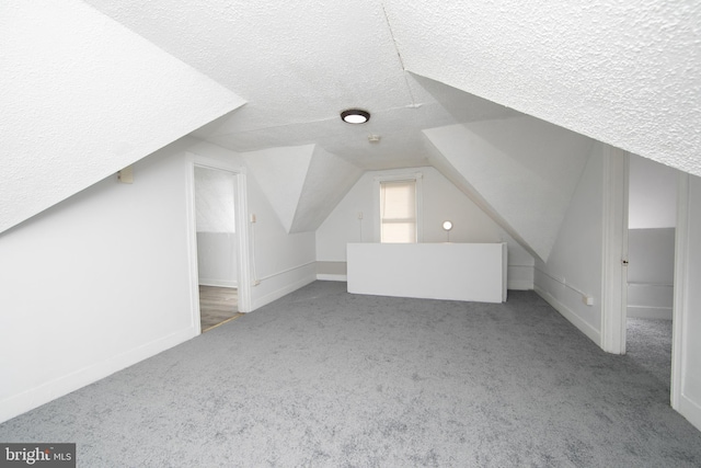 bonus room with carpet flooring, a textured ceiling, and vaulted ceiling