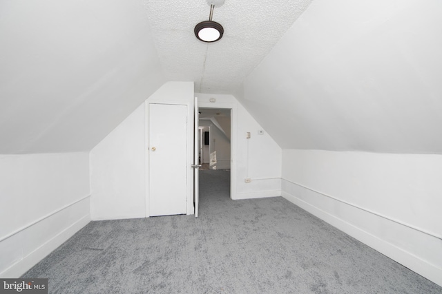 bonus room featuring vaulted ceiling, light carpet, and a textured ceiling