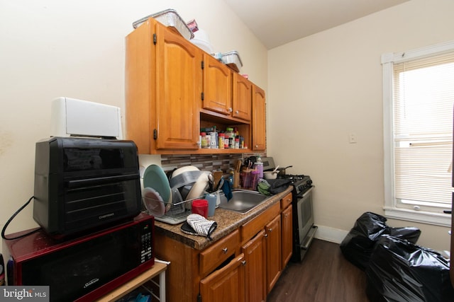 kitchen featuring black gas range, dark hardwood / wood-style floors, and tasteful backsplash