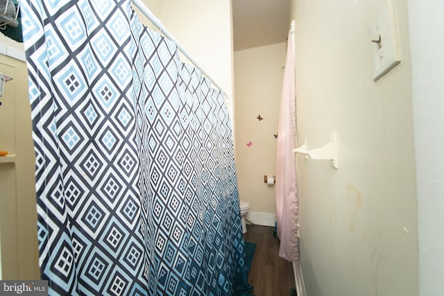 bathroom with hardwood / wood-style flooring, toilet, and curtained shower