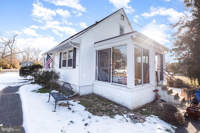 snow covered property featuring a sunroom