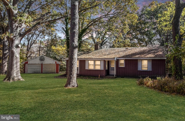 ranch-style house featuring a garage, an outdoor structure, and a yard