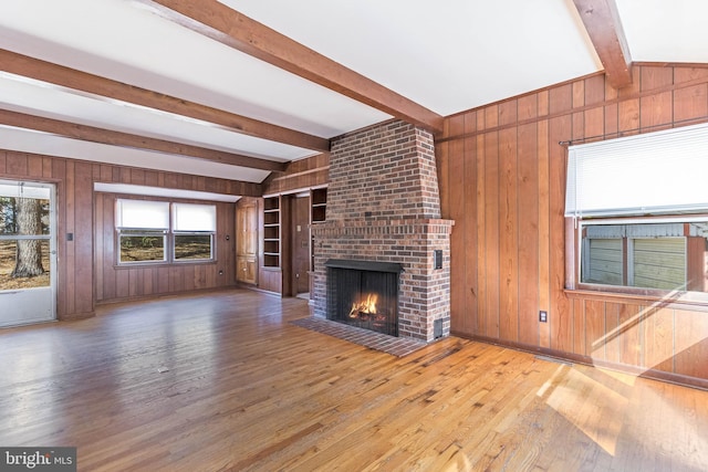 unfurnished living room with wood walls, wood-type flooring, and a brick fireplace