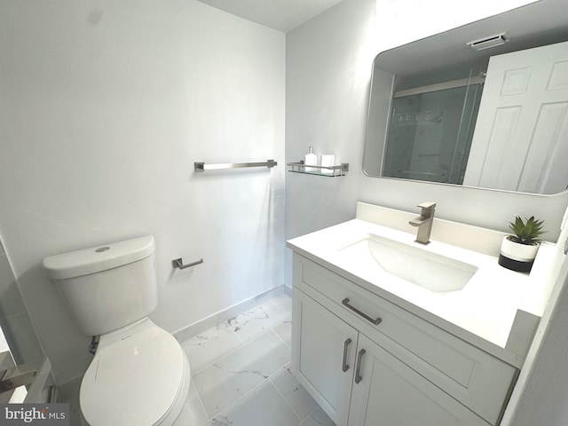 bathroom featuring vanity, marble finish floor, toilet, baseboards, and a stall shower