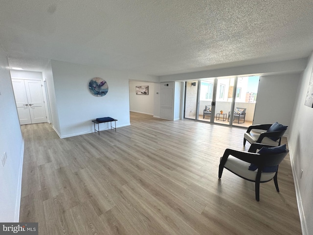 interior space featuring baseboards, a textured ceiling, and light wood-style flooring