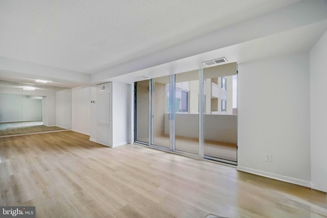 spare room with baseboards, wood finished floors, and visible vents