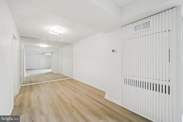 hall with baseboards and light wood finished floors