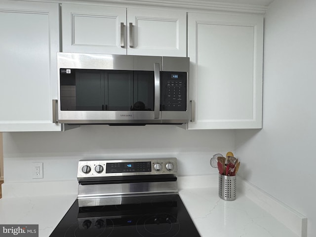 details with light stone countertops, stainless steel appliances, and white cabinetry
