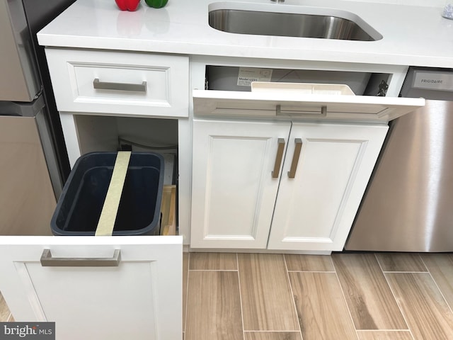 interior details with white cabinets, light countertops, a sink, and dishwasher