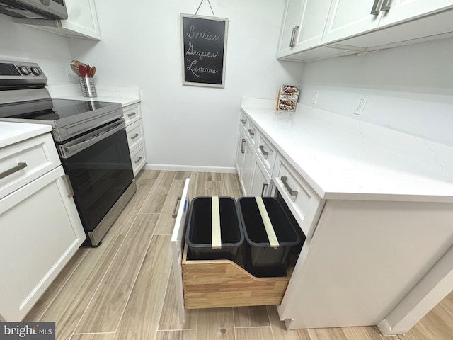 kitchen with light wood-style floors, electric stove, and white cabinets
