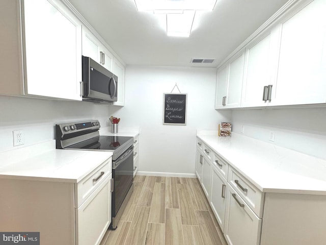 kitchen featuring visible vents, appliances with stainless steel finishes, light countertops, white cabinets, and light wood-style floors