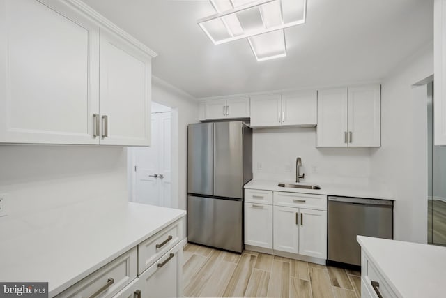 kitchen featuring a sink, appliances with stainless steel finishes, white cabinets, and light countertops