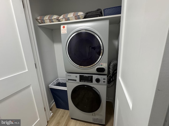 laundry room featuring laundry area, stacked washer and clothes dryer, and light wood-style flooring