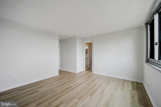 empty room featuring baseboards, a textured ceiling, and wood finished floors