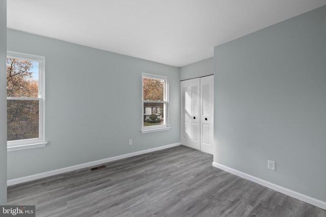 unfurnished bedroom featuring a closet, multiple windows, and hardwood / wood-style floors