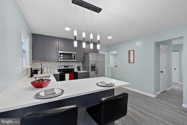 kitchen with kitchen peninsula, appliances with stainless steel finishes, hanging light fixtures, and a kitchen breakfast bar