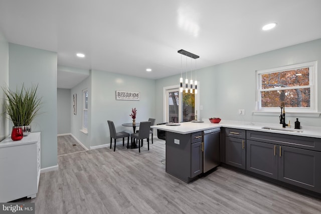 kitchen with hanging light fixtures, sink, light hardwood / wood-style floors, stainless steel dishwasher, and kitchen peninsula