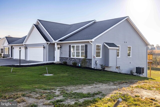 ranch-style house with an attached garage, central AC, driveway, a front yard, and roof with shingles
