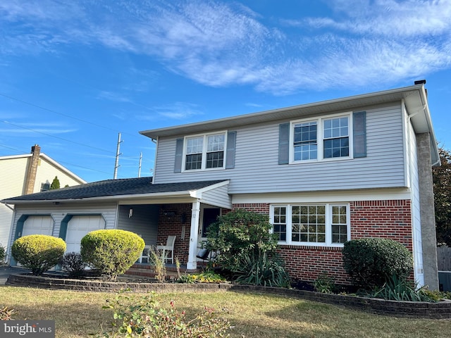 view of property featuring covered porch, a garage, and a front yard