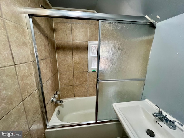 bathroom featuring enclosed tub / shower combo and sink