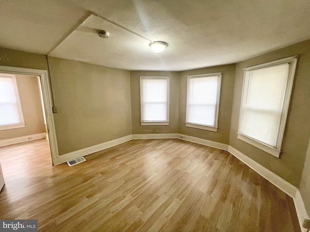 empty room with a textured ceiling and light hardwood / wood-style floors