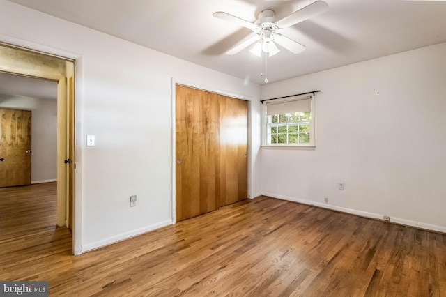 unfurnished bedroom with ceiling fan, wood-type flooring, and a closet