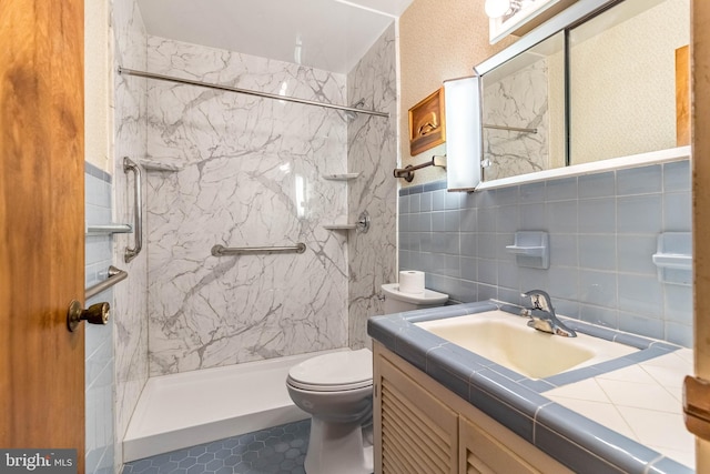 bathroom featuring tile walls, vanity, toilet, and a tile shower