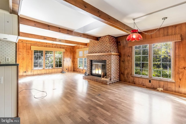 unfurnished living room featuring hardwood / wood-style flooring, a healthy amount of sunlight, and wooden walls