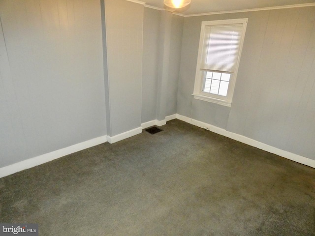 empty room featuring crown molding and dark carpet