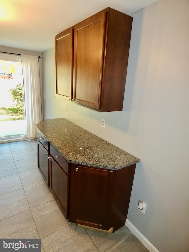 kitchen with light tile patterned floors and dark stone counters