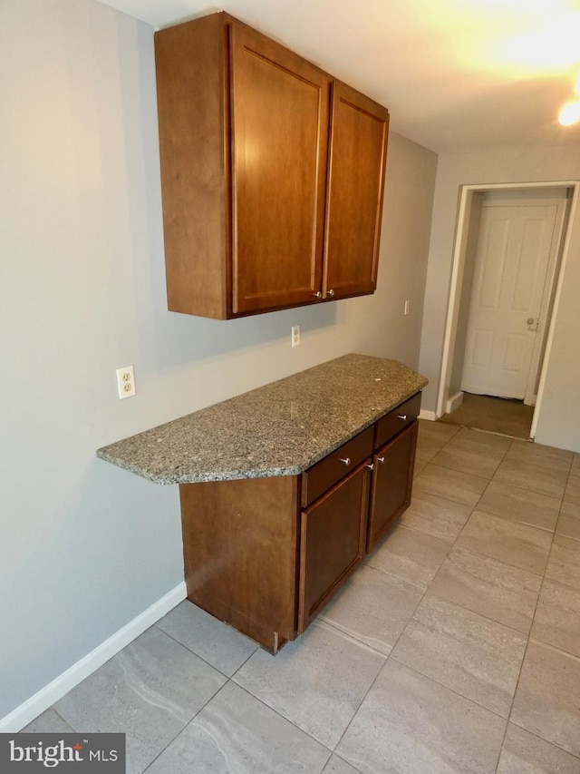 kitchen featuring built in desk, light stone counters, and light tile patterned floors