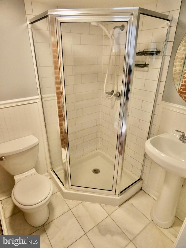 bathroom featuring sink, a shower with shower door, toilet, and tile patterned flooring