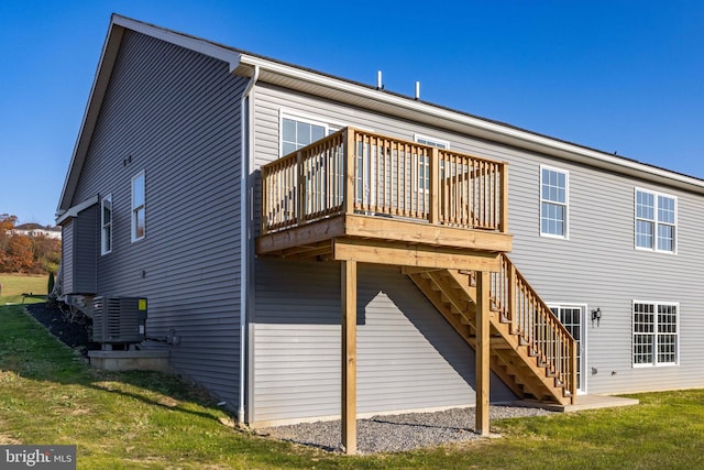 rear view of house with central AC, a deck, and a lawn